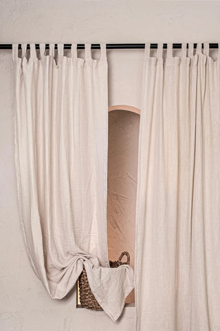 Beige tab top panels on black rod, niche. Handwoven 2-layer muslin cotton curtain, Denizli, OEKO-TEX. Vivamaison.