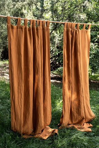 Cinnamon tab top panels outdoors on grass. Handwoven 2-layer muslin cotton curtain, Denizli, OEKO-TEX. Vivamaison.