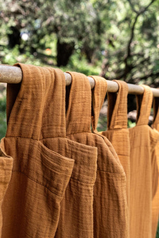 Cinnamon tab loops closeup, garden bokeh. Handwoven 2-layer muslin cotton curtain, Denizli, OEKO-TEX. Vivamaison.