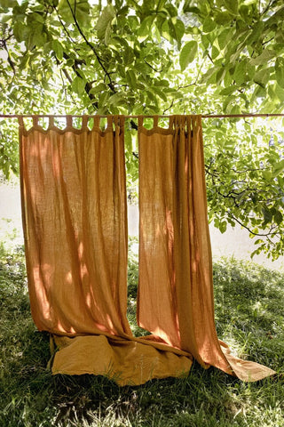Golden ochre panels hanging in garden. Handwoven 2-layer muslin cotton curtain, Denizli, OEKO-TEX. Vivamaison.