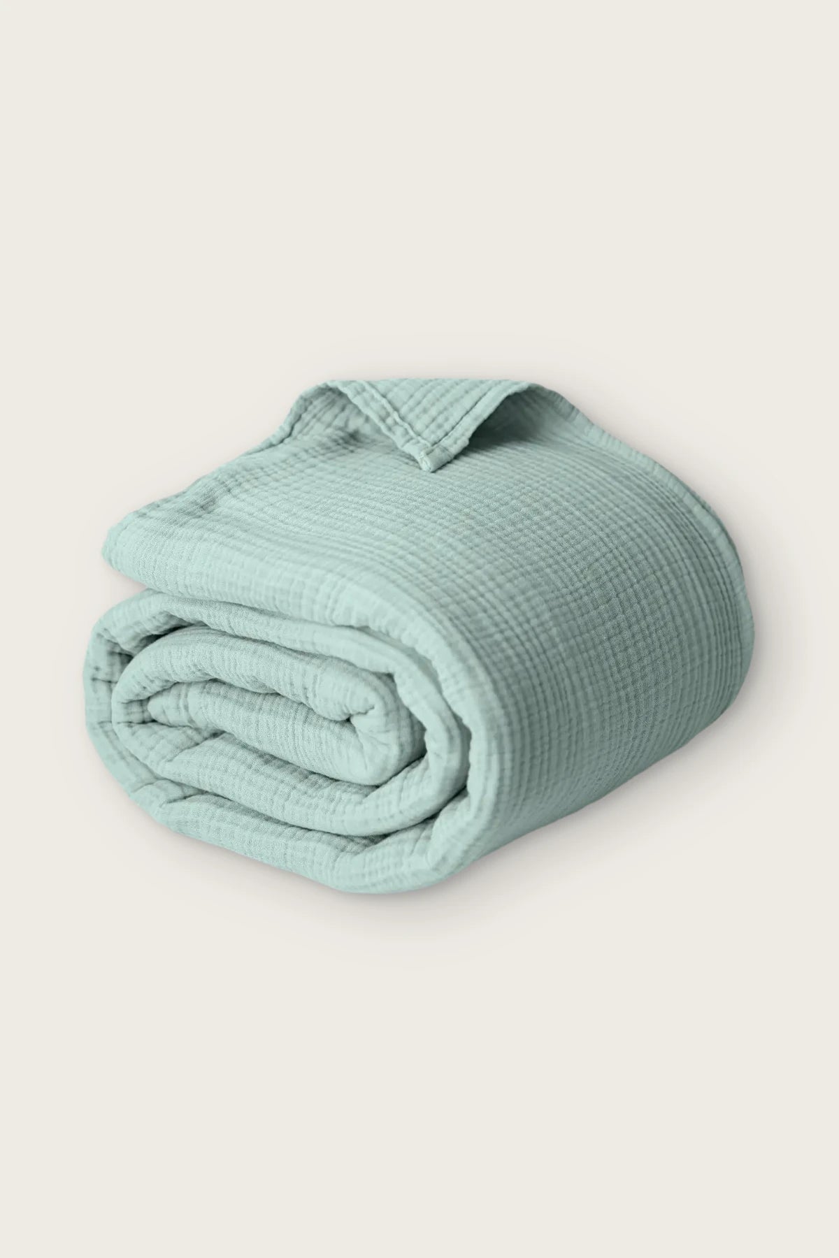 Handwoven 4-layer muslin cotton bedspread in sage green, rolled front view