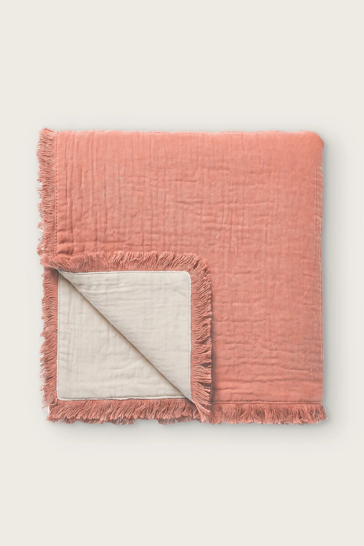 Handwoven 4-layer soft muslin fringed bedspread in terracotta, folded front view showing reversible cream side
