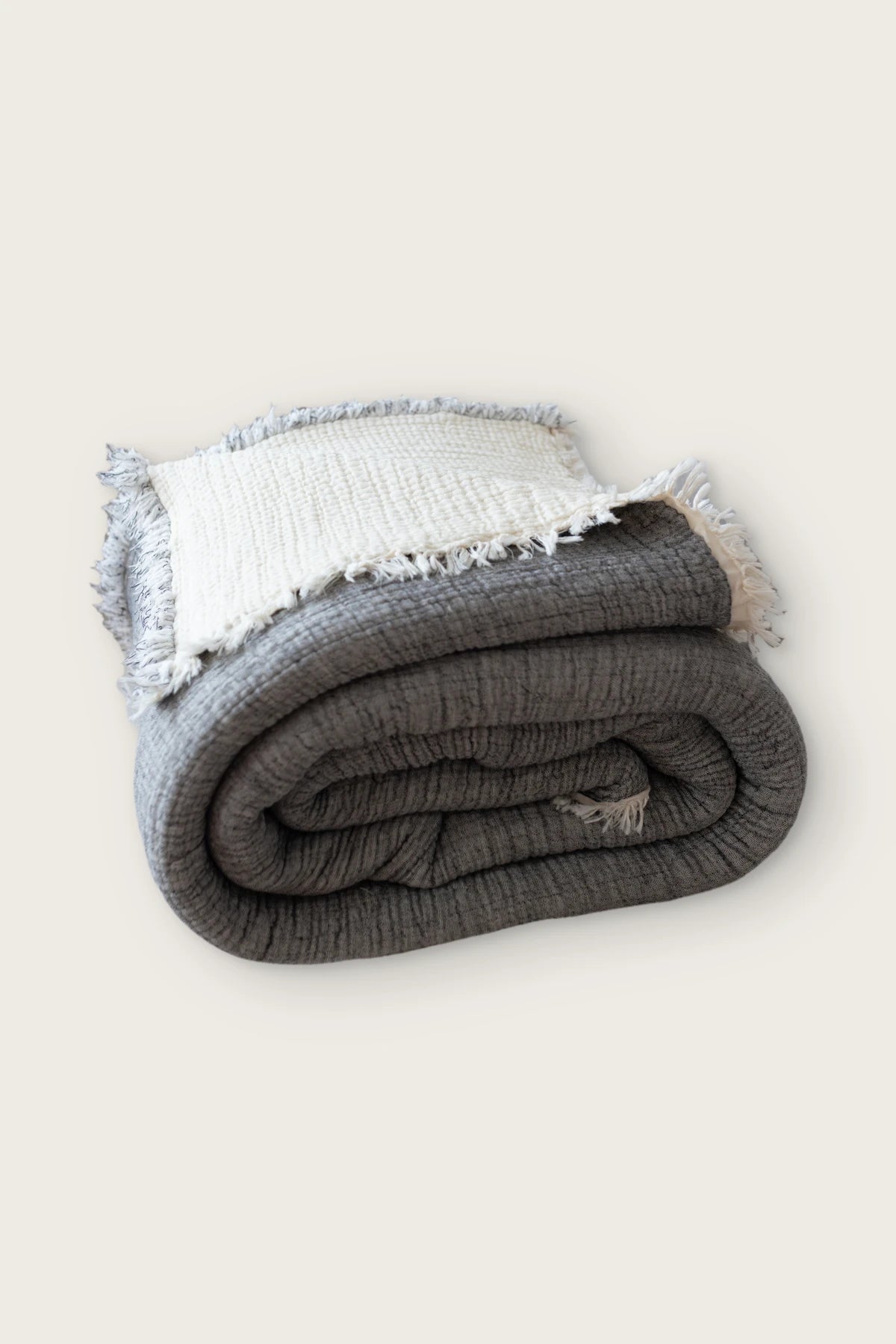 Handwoven 8-layer muslin Turkish cotton quilt in dark gray, rolled front view with hand-tied fringe