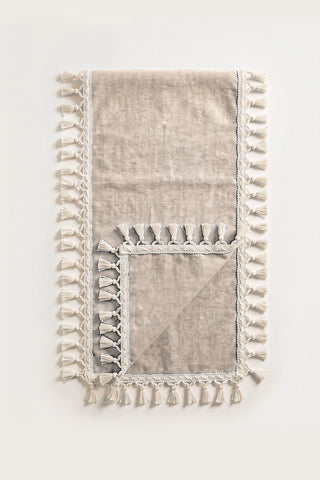 Handwoven Turkish cotton tassel table runner in brown, folded in half with corner turned back showing the tassel trim