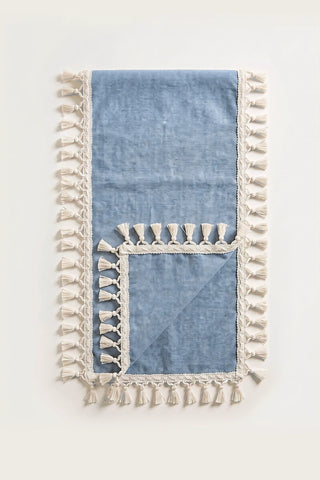 Handwoven Turkish cotton tassel table runner in navy blue, folded in half with corner turned back showing the tassel trim