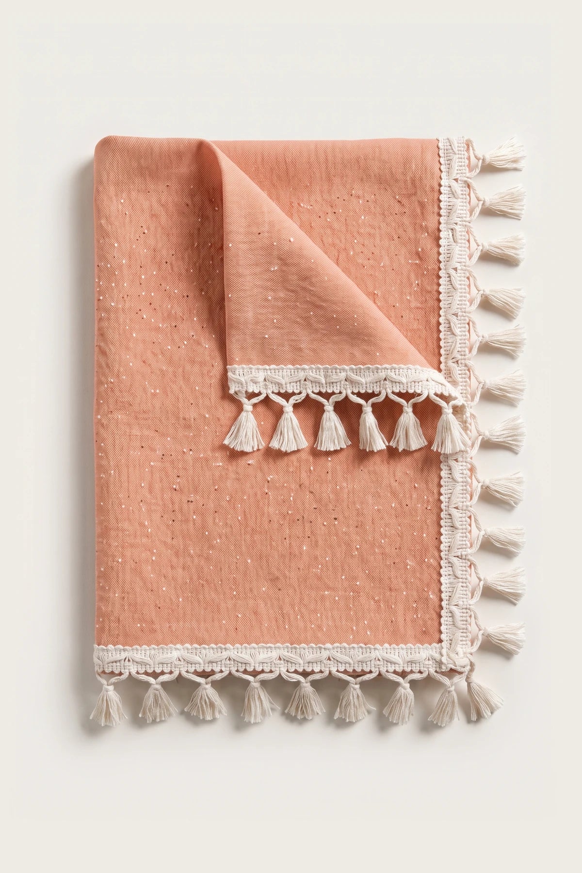 Handwoven Turkish cotton tassel tablecloth in orange, folded with corner turned back showing the tassel trim