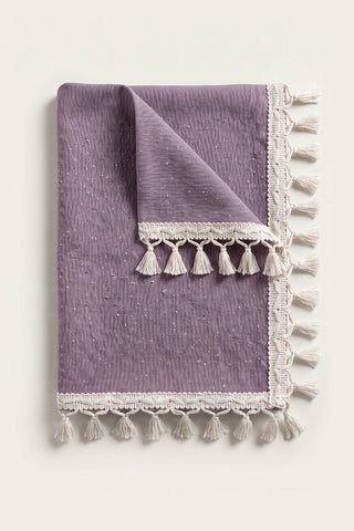 Handwoven Turkish cotton tassel tablecloth in plum, folded with corner turned back showing the tassel trim
