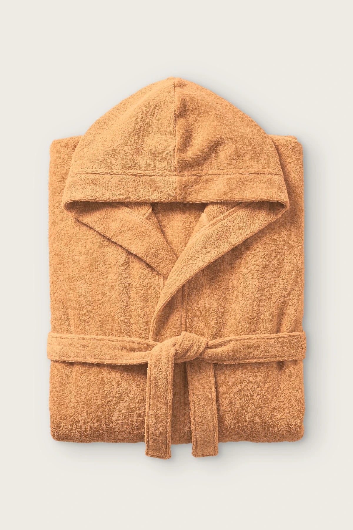Handwoven Turkish cotton terry hooded bathrobe in orange, folded front view with hood and tied belt