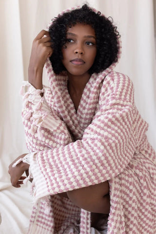 Light pink mosaic bathrobe hood up seated closeup. Handwoven Turkish cotton Denizli, OEKO-TEX. Vivamaison.