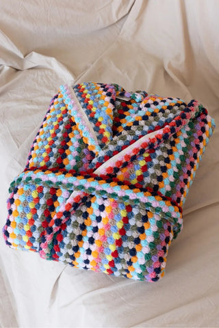 Rainbow mosaic bathrobe folded flat lay on bed. Handwoven Turkish cotton Denizli, OEKO-TEX. Vivamaison.