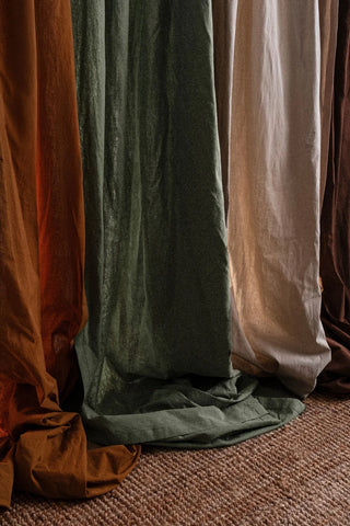 Hem detail of multiple stonewashed cotton curtain colors over a rug. Handwoven in Denizli, OEKO-TEX. Vivamaison.