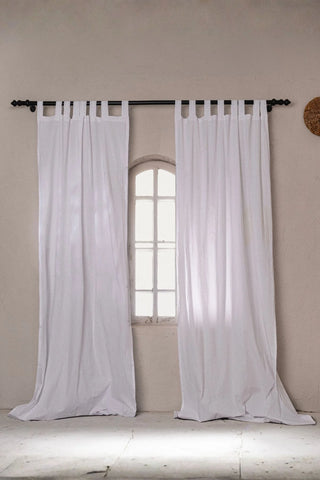 White stonewashed cotton curtain panels framing an arched window. Handwoven in Denizli, OEKO-TEX. Vivamaison.