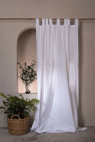 White stonewashed cotton curtain panel, tab top, beside an arched niche. Handwoven in Denizli, OEKO-TEX. Vivamaison.