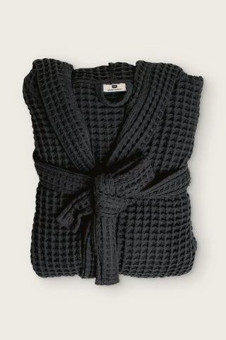 Handwoven waffle hooded bathrobe in black, folded front view with tied belt