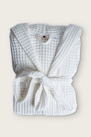 Handwoven waffle hooded bathrobe in white, folded front view with tied belt