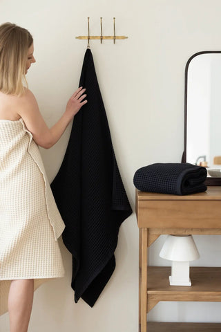 Black handwoven Turkish cotton waffle weave towel lifestyle shoulder drop. Denizli, OEKO-TEX. Vivamaison.