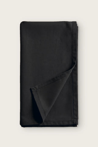 Plain linen cotton blend table runner in black, folded in half with corner turned back