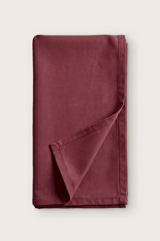 Plain linen cotton blend table runner in burgundy, folded in half with corner turned back