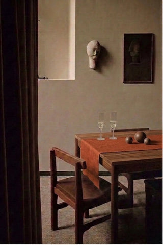 Cinnamon plain linen cotton blend table runner on a dining table with champagne flutes, seen through a doorway. 16 x 51 in, handmade in Denizli, OEKO-TEX. VivaMaison.
