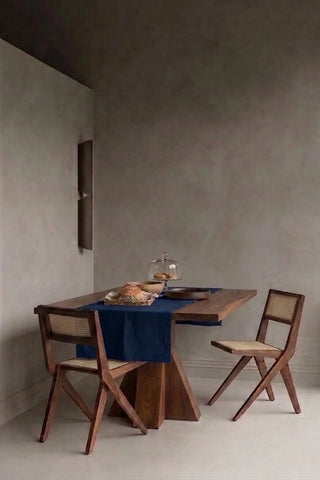 Navy plain linen cotton blend table runner styled in a modern dining room with cane chairs. 16 x 51 in, handmade in Denizli, OEKO-TEX. VivaMaison.