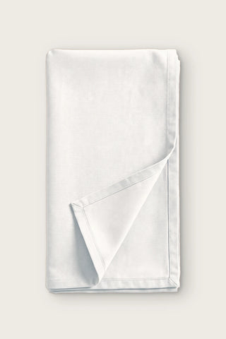 Plain linen cotton blend table runner in white, folded in half with corner turned back