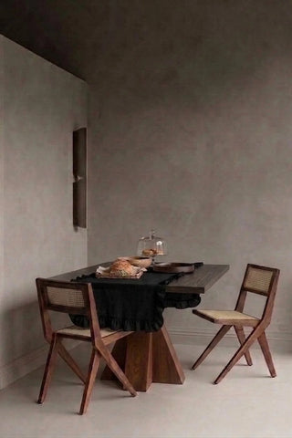 Black ruffled linen cotton blend table runner styled in a modern dining room with cane chairs. 16 x 51 in, handmade in Denizli, OEKO-TEX. VivaMaison.