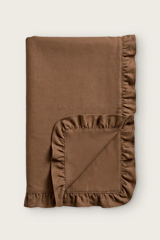 Ruffled linen cotton blend table runner in brown, folded in half with corner turned back