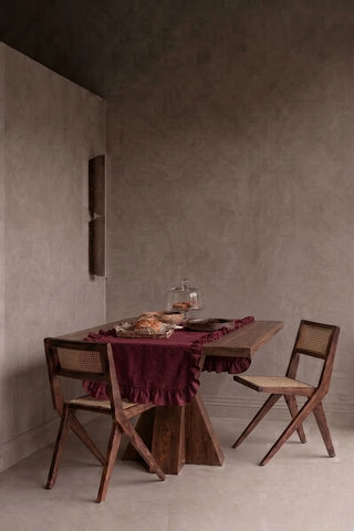 Burgundy ruffled linen cotton blend table runner styled in a modern dining room with cane chairs. 16 x 51 in, handmade in Denizli, OEKO-TEX. VivaMaison.