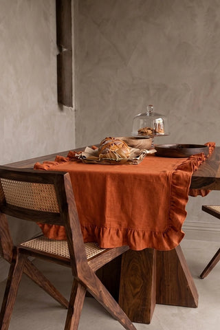 Cinnamon ruffled linen cotton blend table runner draped over a walnut dining table with a bread basket and wooden bowls. 16 x 51 in, handmade in Denizli, OEKO-TEX. VivaMaison.