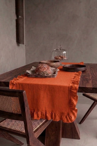 Cinnamon ruffled linen cotton blend table runner draped over a walnut dining table with a bread basket and wooden bowls. 16 x 51 in, handmade in Denizli, OEKO-TEX. VivaMaison.