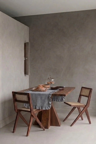 Gray ruffled linen cotton blend table runner styled in a modern dining room with cane chairs. 16 x 51 in, handmade in Denizli, OEKO-TEX. VivaMaison.