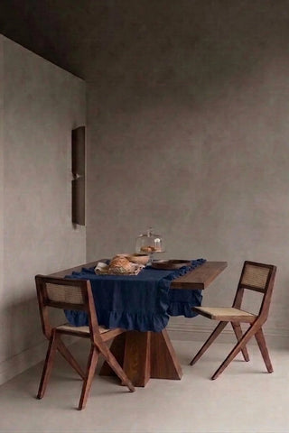 Navy ruffled linen cotton blend table runner styled in a modern dining room with cane chairs. 16 x 51 in, handmade in Denizli, OEKO-TEX. VivaMaison.