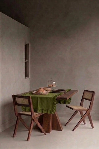 Olive Green ruffled linen cotton blend table runner styled in a modern dining room with cane chairs. 16 x 51 in, handmade in Denizli, OEKO-TEX. VivaMaison.