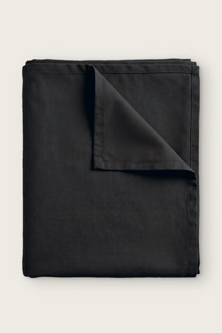 Plain linen cotton blend tablecloth in black, folded with corner turned back