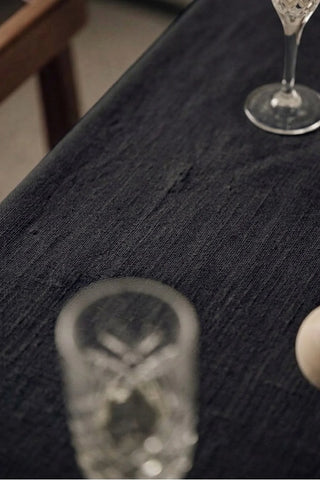 Black plain linen cotton blend tablecloth fabric texture close-up with a wine glass. 9 sizes, handmade in Denizli, OEKO-TEX. VivaMaison.