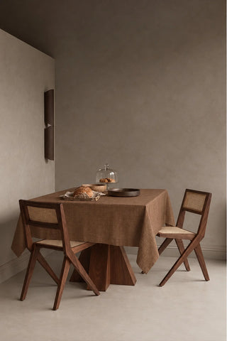 Brown plain linen cotton blend tablecloth on a dining table in a modern dining room with cane chairs. 9 sizes, handmade in Denizli, OEKO-TEX. VivaMaison.