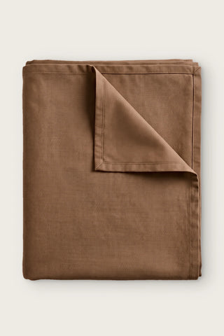 Plain linen cotton blend tablecloth in brown, folded with corner turned back