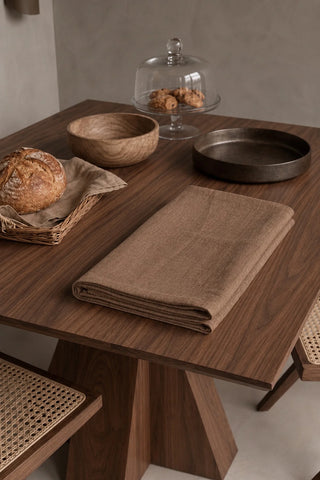Brown plain linen cotton blend tablecloth folded on a walnut dining table beside a bread basket. 9 sizes, handmade in Denizli, OEKO-TEX. VivaMaison.