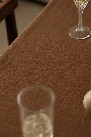 Brown plain linen cotton blend tablecloth fabric texture close-up with a wine glass. 9 sizes, handmade in Denizli, OEKO-TEX. VivaMaison.