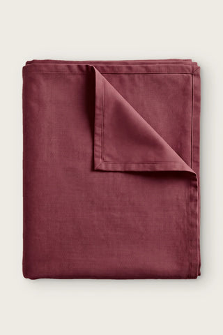 Plain linen cotton blend tablecloth in burgundy, folded with corner turned back