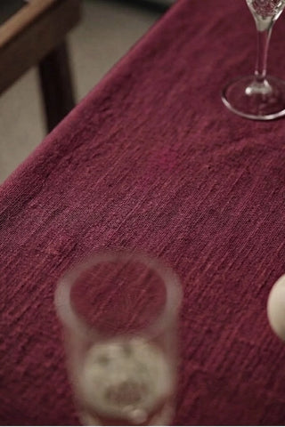 Burgundy plain linen cotton blend tablecloth fabric texture close-up with a wine glass. 9 sizes, handmade in Denizli, OEKO-TEX. VivaMaison.