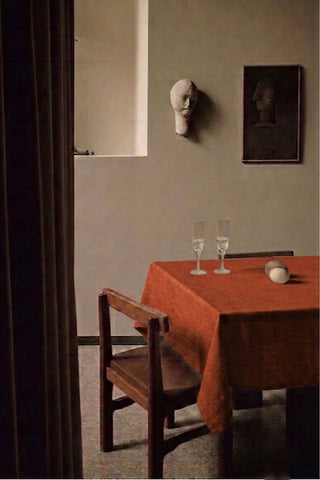 Cinnamon plain linen cotton blend tablecloth on a dining table with champagne flutes, seen through a doorway. 9 sizes, handmade in Denizli, OEKO-TEX. VivaMaison.