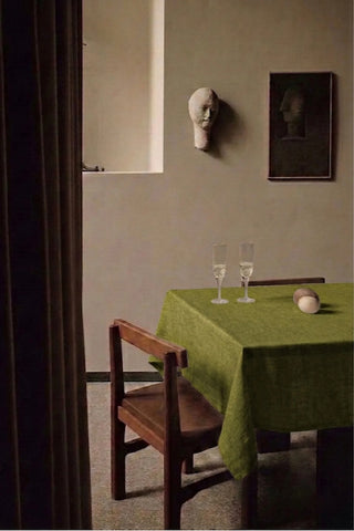 Olive Green plain linen cotton blend tablecloth on a dining table with champagne flutes, seen through a doorway. 9 sizes, handmade in Denizli, OEKO-TEX. VivaMaison.