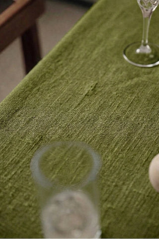 Olive Green plain linen cotton blend tablecloth fabric texture close-up with a wine glass. 9 sizes, handmade in Denizli, OEKO-TEX. VivaMaison.