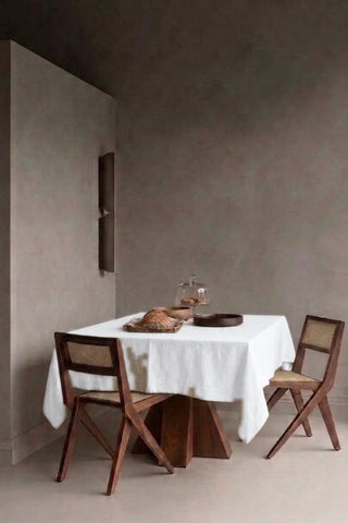 White plain linen cotton blend tablecloth on a dining table in a modern dining room with cane chairs. 9 sizes, handmade in Denizli, OEKO-TEX. VivaMaison.
