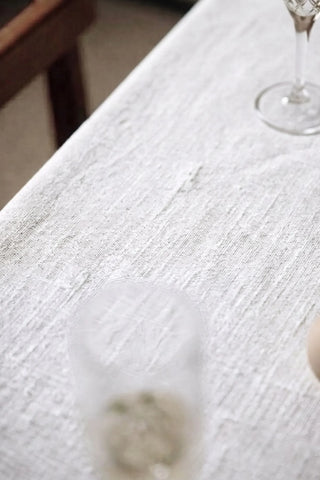 White plain linen cotton blend tablecloth fabric texture close-up with a wine glass. 9 sizes, handmade in Denizli, OEKO-TEX. VivaMaison.