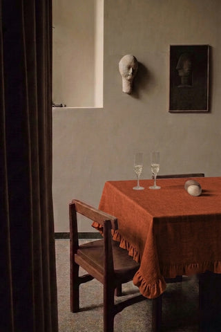 Cinnamon ruffled linen cotton blend tablecloth on a dining table with champagne flutes, seen through a doorway. 9 sizes, handmade in Denizli, OEKO-TEX. VivaMaison.