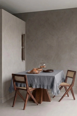 Gray ruffled linen cotton blend tablecloth on a dining table in a modern dining room with cane chairs. 9 sizes, handmade in Denizli, OEKO-TEX. VivaMaison.