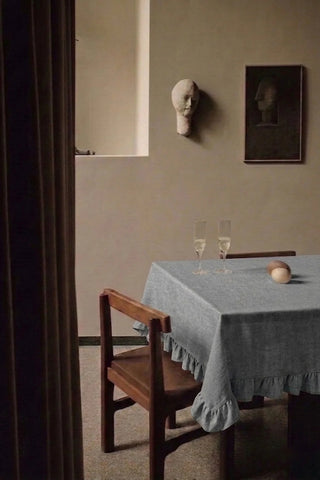 Gray ruffled linen cotton blend tablecloth on a dining table with champagne flutes, seen through a doorway. 9 sizes, handmade in Denizli, OEKO-TEX. VivaMaison.