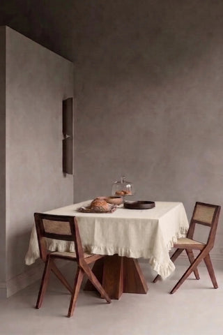Natural ruffled linen cotton blend tablecloth on a dining table in a modern dining room with cane chairs. 9 sizes, handmade in Denizli, OEKO-TEX. VivaMaison.